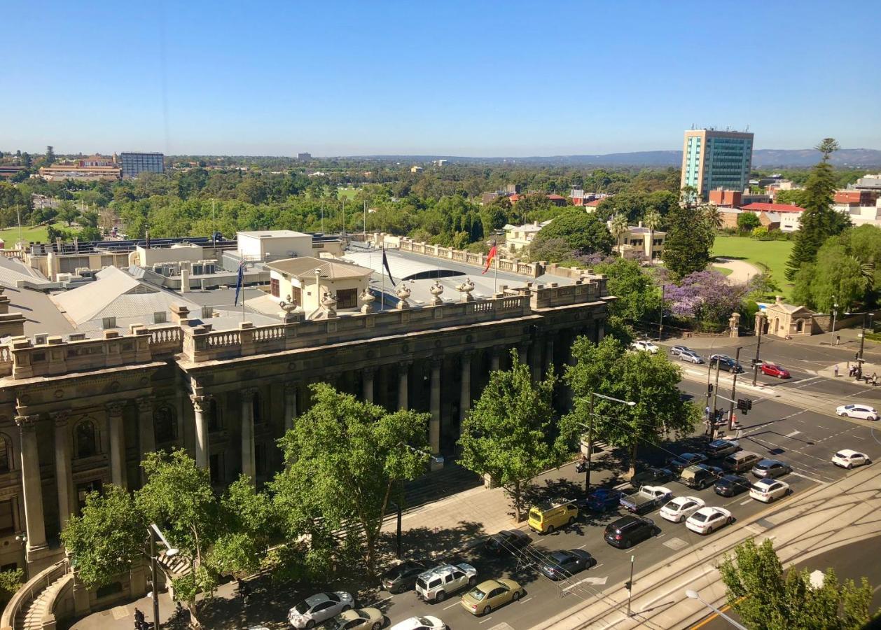 Stamford Plaza Adelaide Hotell Exteriör bild The photo depicts a cityscape view, showcasing a mix of architectural structures and greenery. In the foreground, there is a large, classical building with columns, suggesting it may be a historical or governmental structure. Surrounding the building